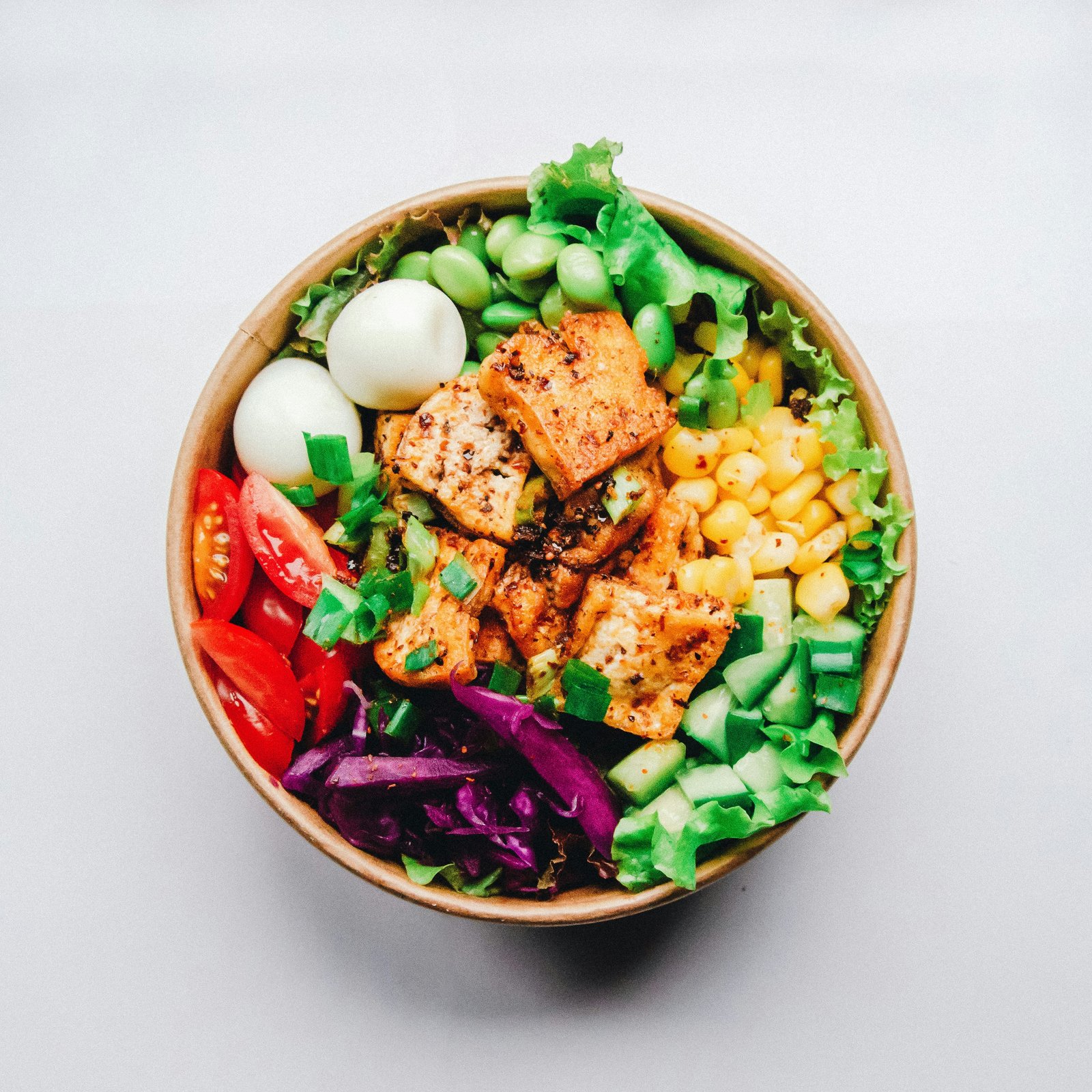 hands tossing fresh salad with wooden spoons